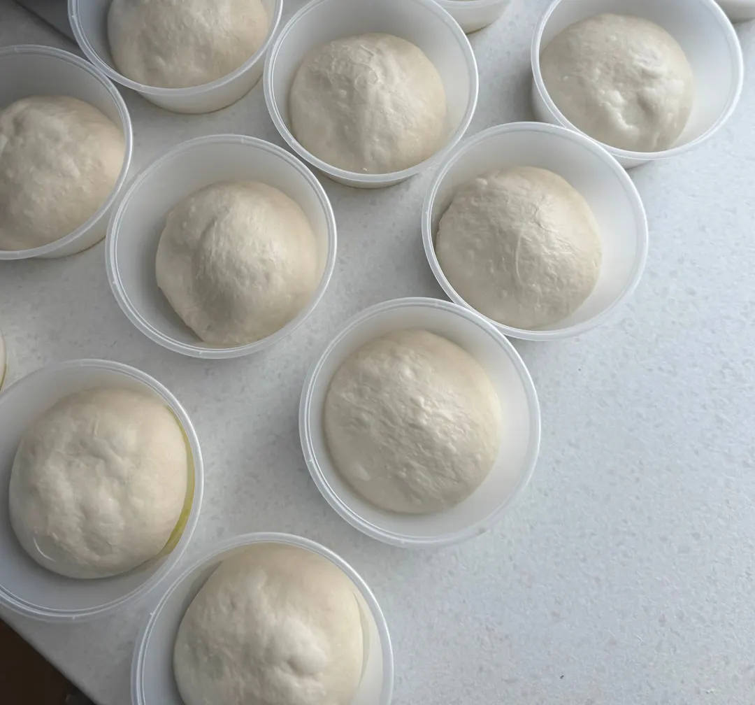 Hevede pizzaballer i hver sin boks, sett ovenfra